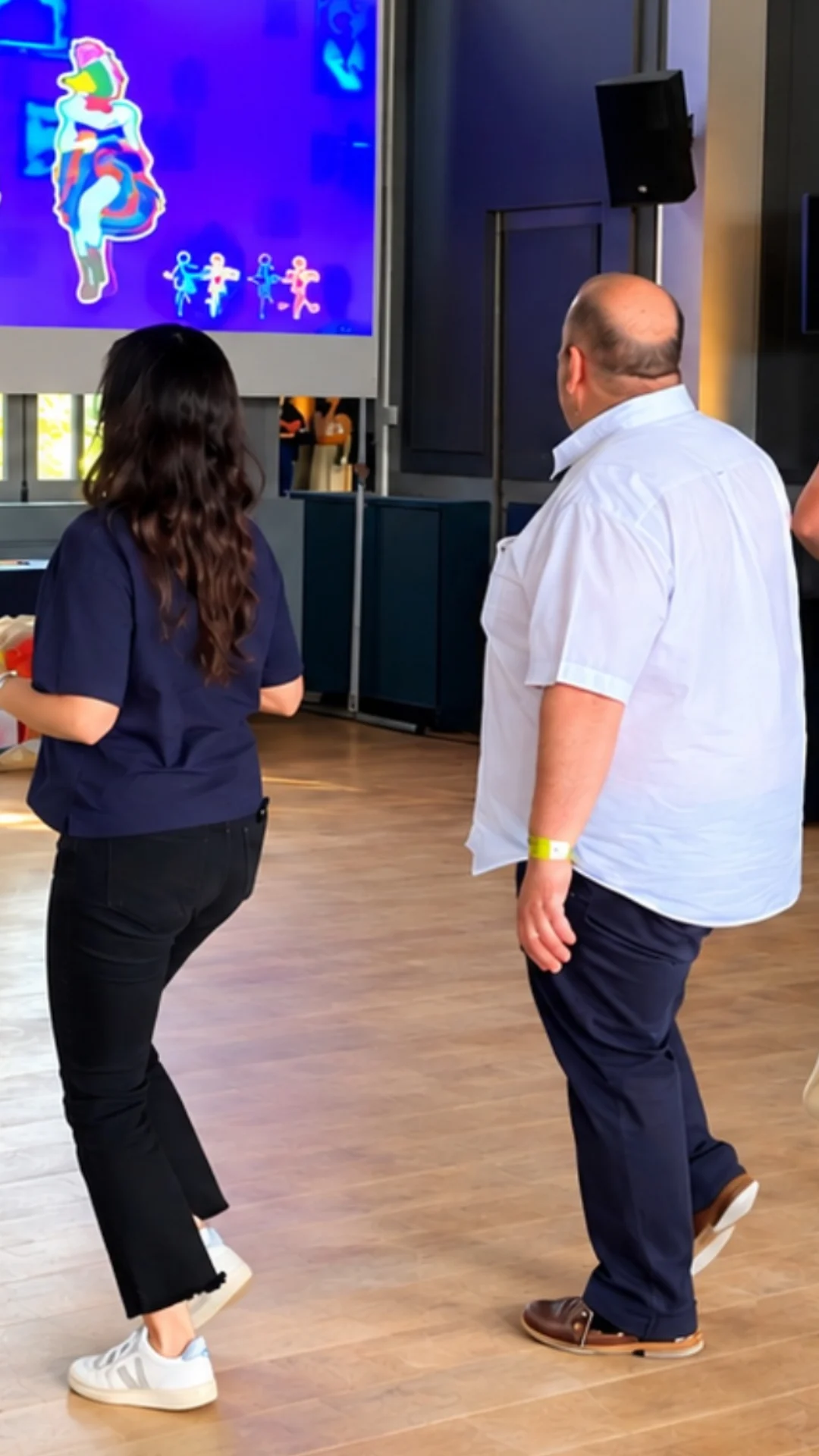 Interaktivní taneční zábava Just Dance pro firmy Skupina kolegů tančí podle předlohy na velkém plátně během interaktivního programu Just Dance na firemním teambuildingu.